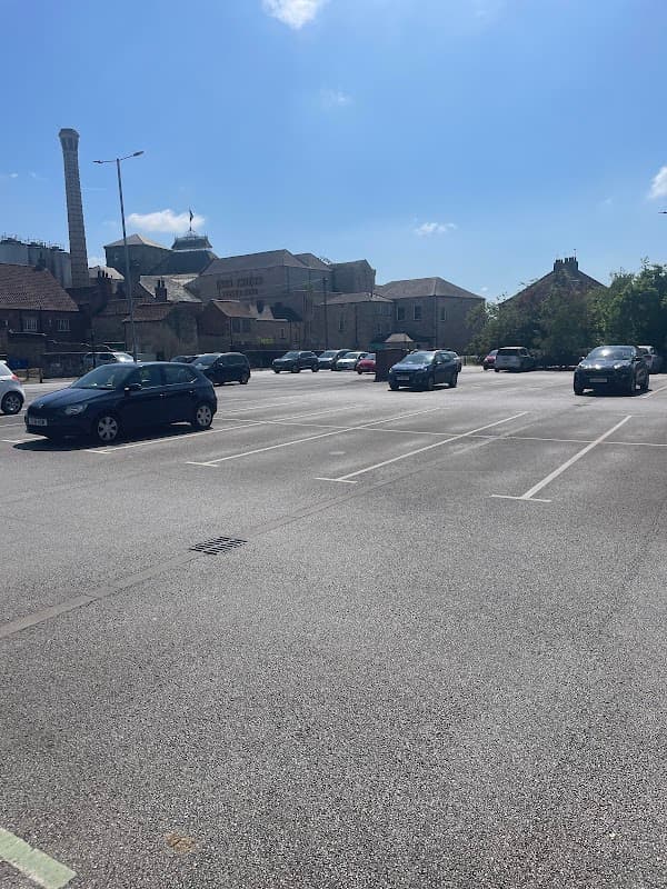 Spacious car park with several parked cars under a clear blue sky, surrounded by buildings in Tadcaster, Yorkshire.