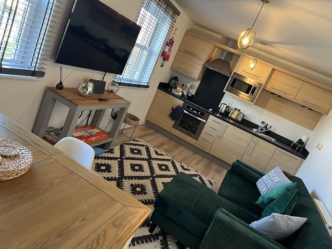 Modern kitchen and cozy living area with green sofa, TV, dining table, and decorative rug in Bay Retreat, Filey.