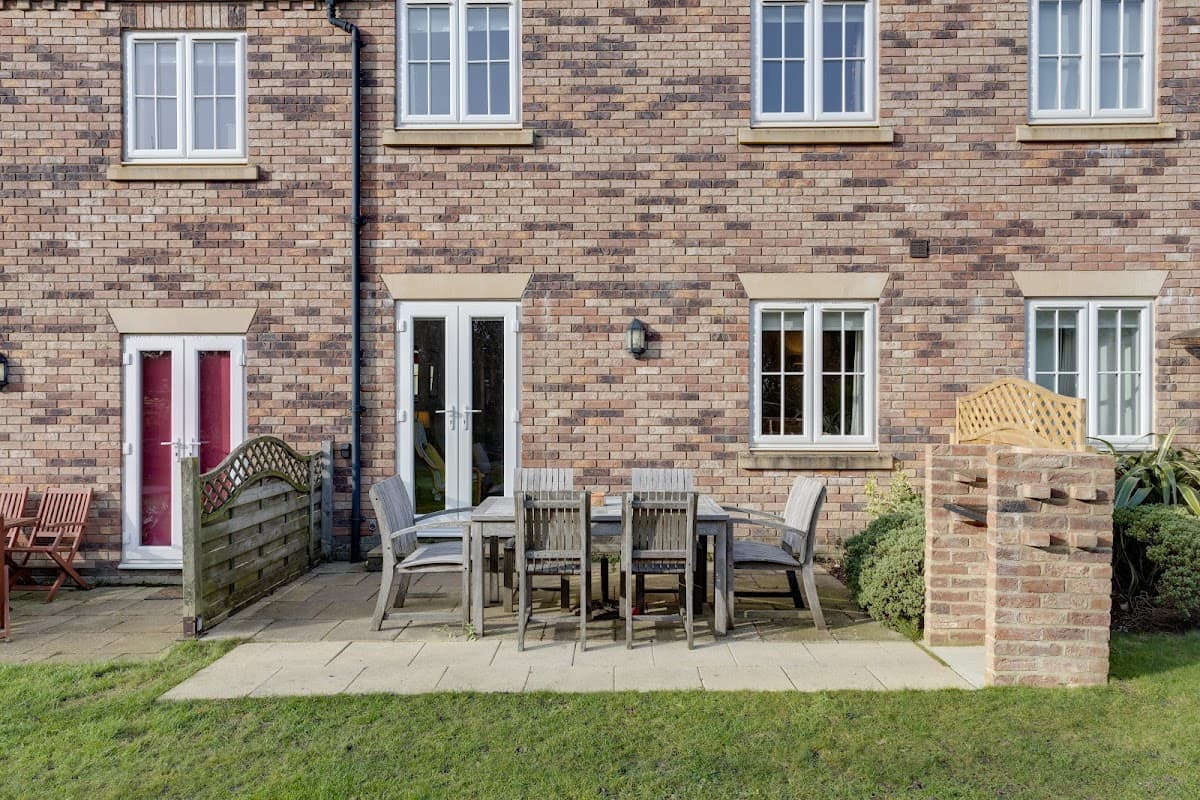 Brick cottage exterior with patio furniture, a wooden fence, and well-maintained greenery in Filey, Yorkshire.