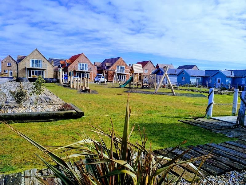 Colorful lodges with playground equipment and grassy areas under a blue sky at Puffin Lodge, Filey.