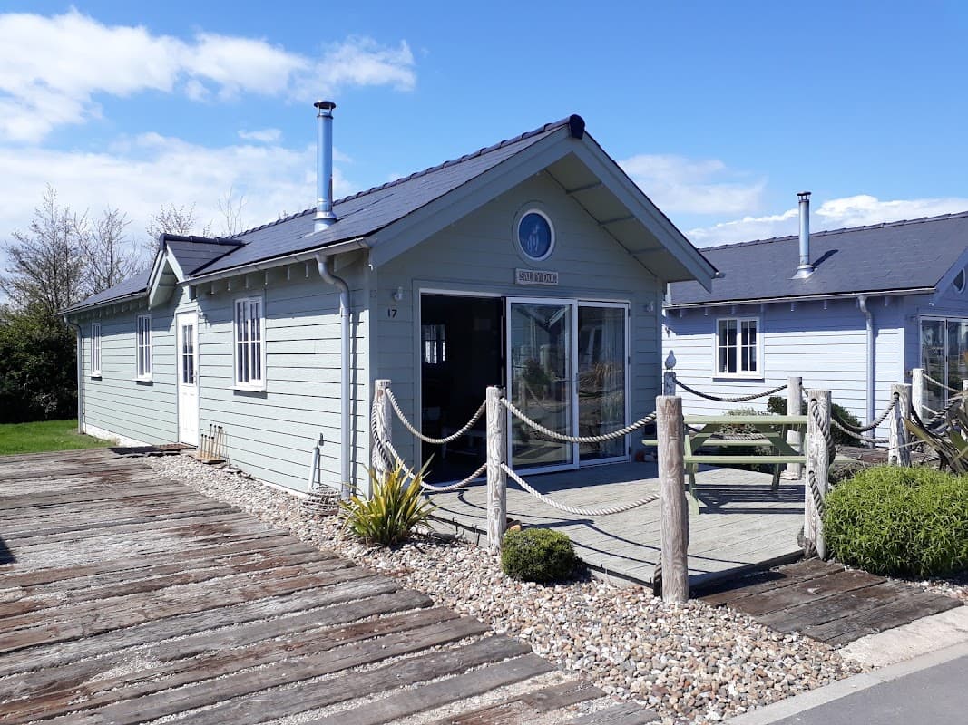 Salty Dog Beach House features a light blue exterior, wooden decking, and a scenic view under a clear sky.