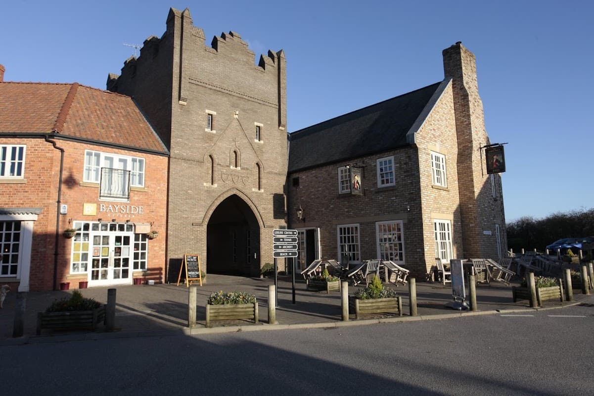 The Happy Plaice Beach House features a unique castle-like structure with outdoor seating and nearby shops.