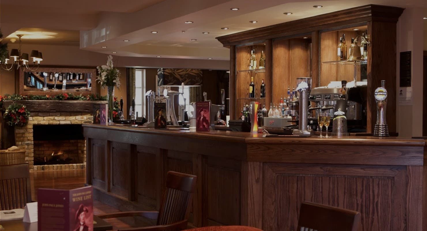 Wooden bar with drinks, cozy fireplace, and festive decorations in a welcoming takeaway setting.