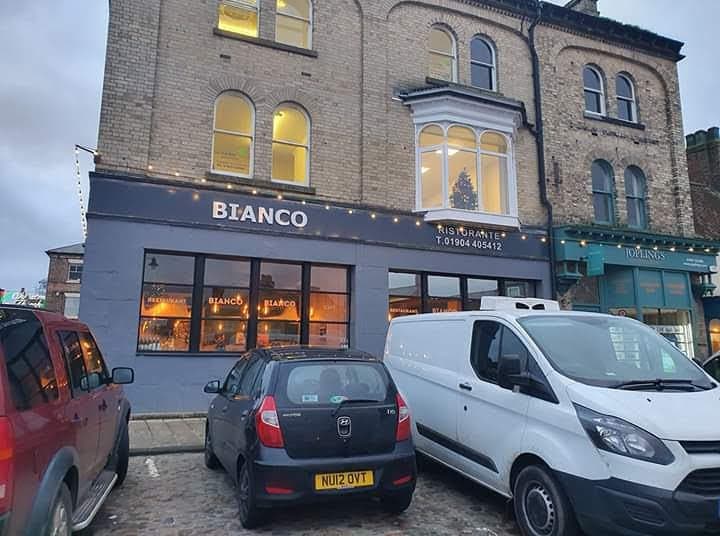 Bianco Ristorante in Thirsk, featuring a festive window display, parked cars, and a charming brick facade.