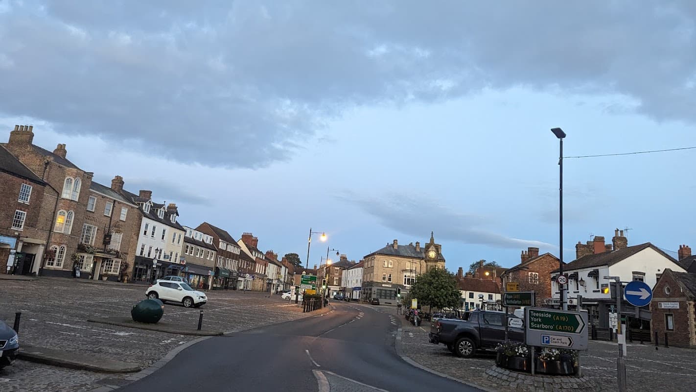Market Place Car Park in Thirsk, featuring cobblestone streets, historic buildings, and street signage.