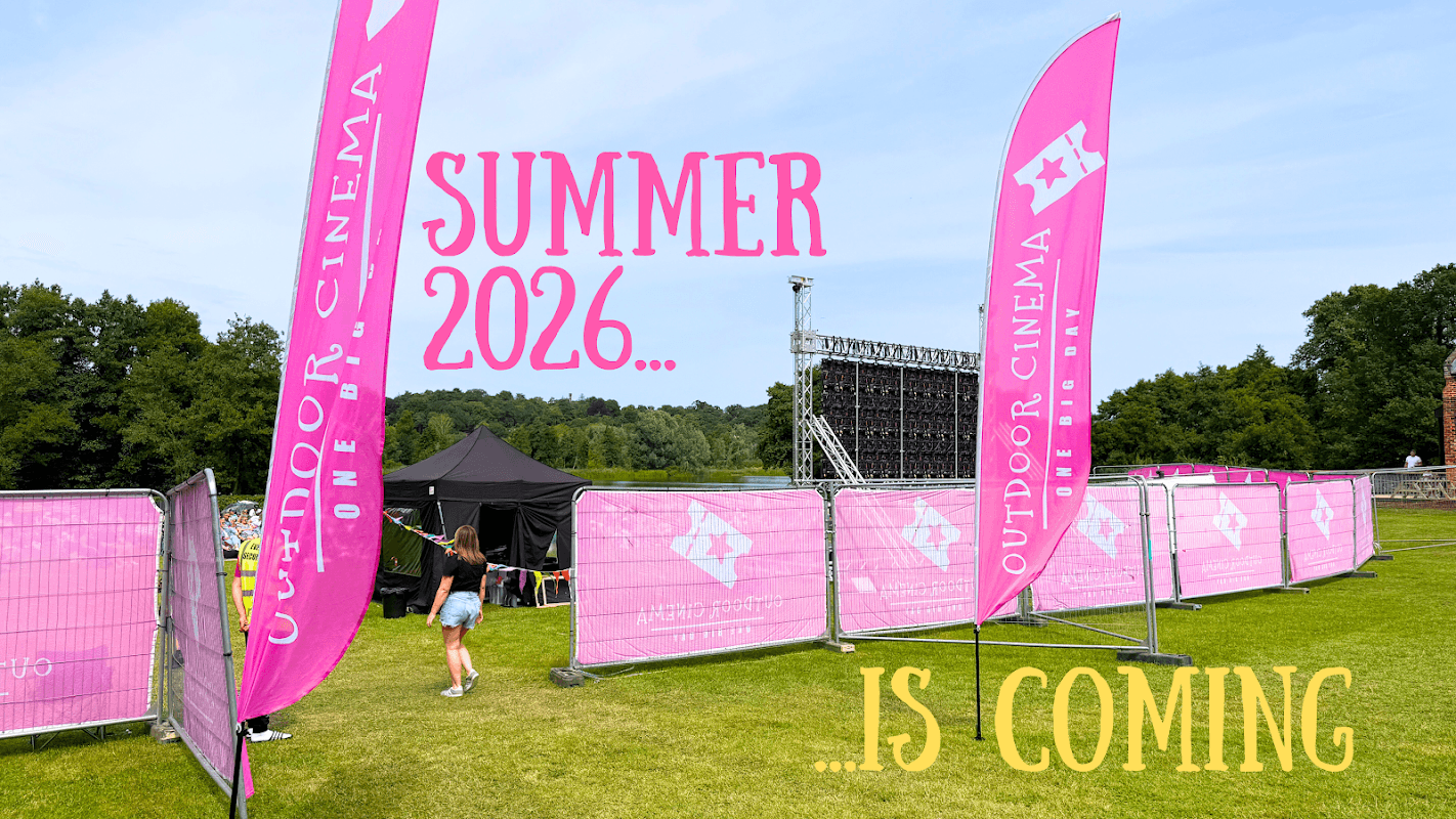 Colorful banners announce "Outdoor Cinema" with a large screen set up on a grassy field, surrounded by fencing.