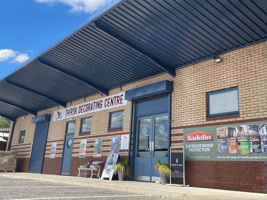 Thirsk Decorating Centre storefront with blue awning, large sign, and promotional banners on brick exterior.