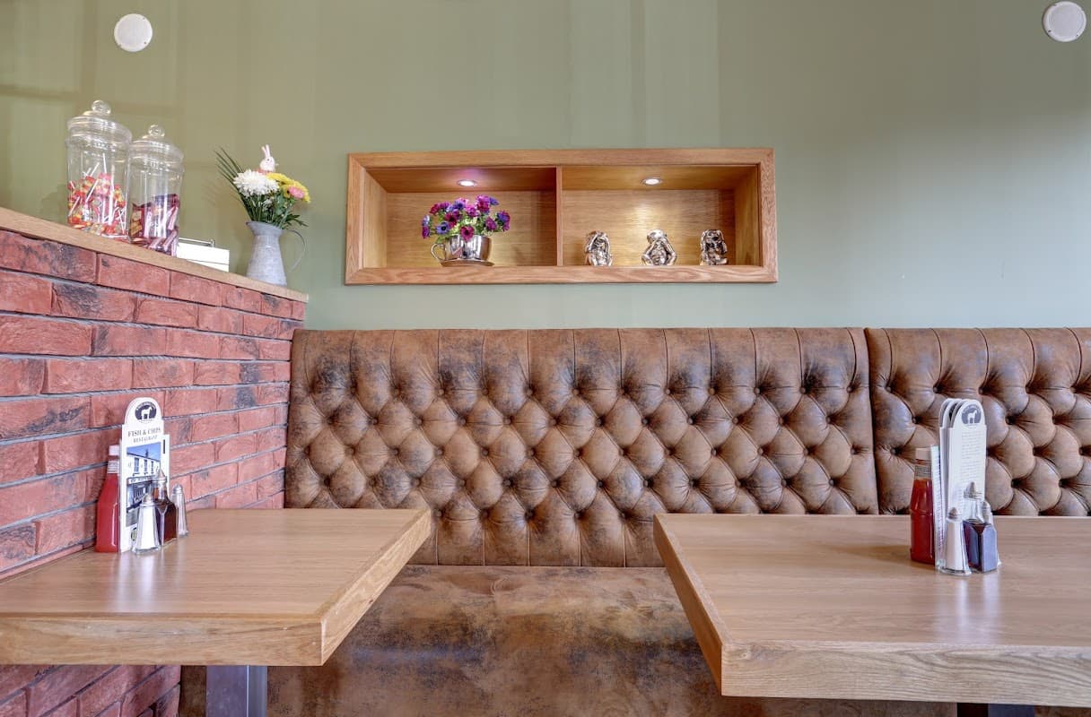 Cozy takeaway interior with tufted brown seating, wooden tables, and decorative shelves with flowers and figurines.