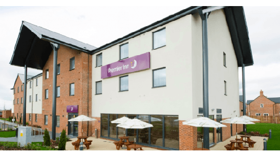 Premier Inn building with a modern design, outdoor seating area, and umbrellas in Thirsk, Yorkshire.