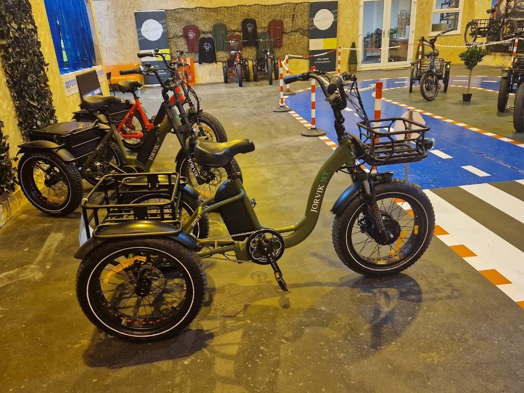 A green Jorvik tricycle with baskets, surrounded by various bikes in a sports shop setting.