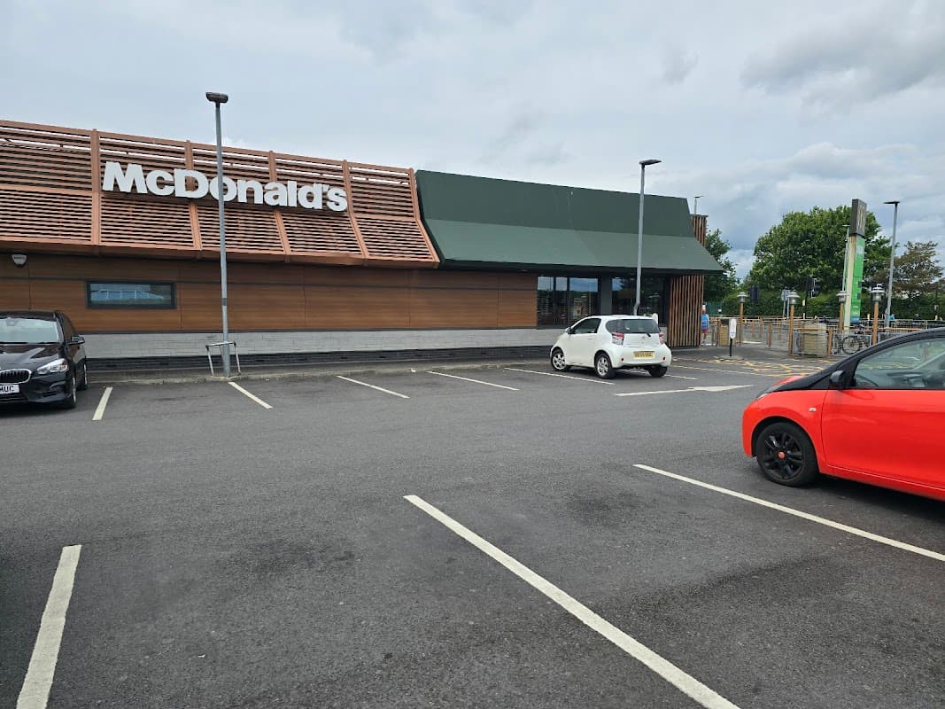 McDonald's restaurant exterior with a parking lot, featuring a wooden facade and green awning.