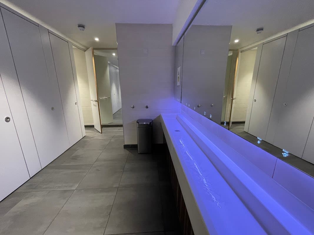 Modern public toilet interior with sleek stalls, a long sink, and ambient lighting. Clean and spacious design.