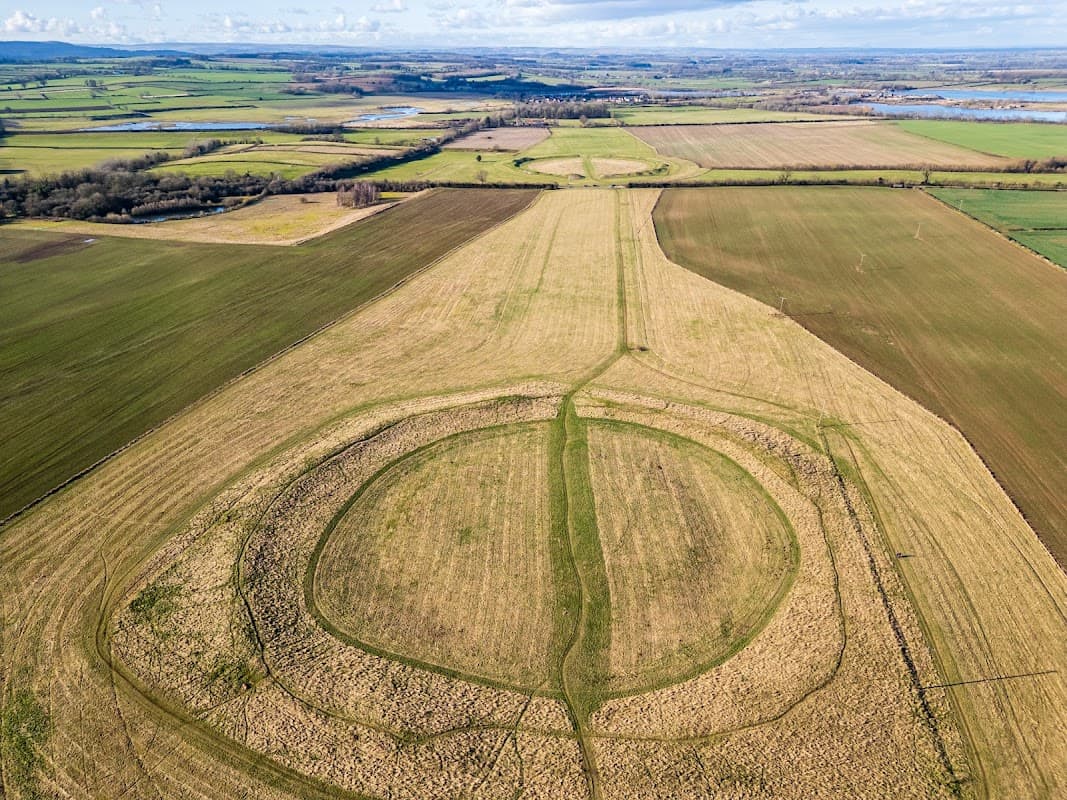 Aerial view of Thornborough Henges, featuring circular earthworks surrounded by green fields and distant hills.