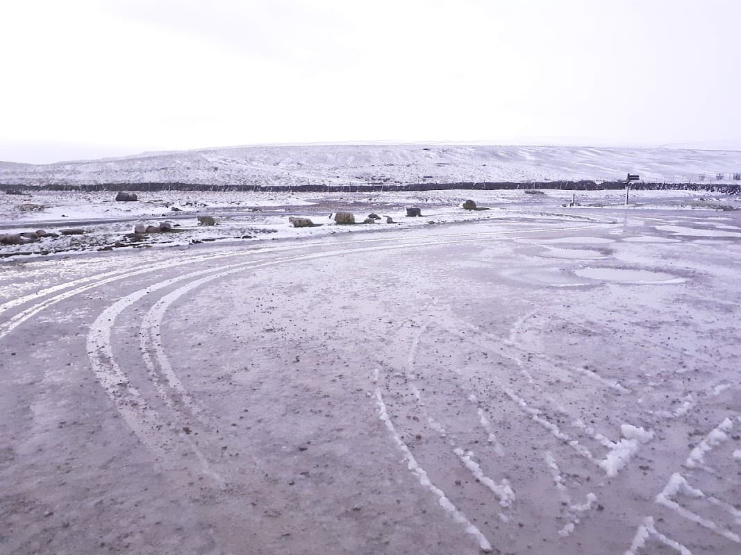 Free parking area with wet, snowy ground and distant hills under a cloudy sky in Thornton, Craven, Yorkshire.