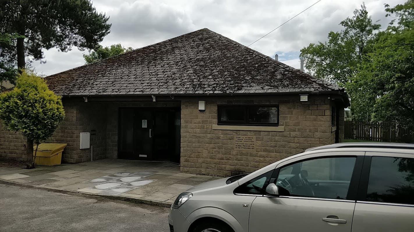 Linden Road Centre, a stone building with a sloped roof, surrounded by trees and parked cars in a rural setting.