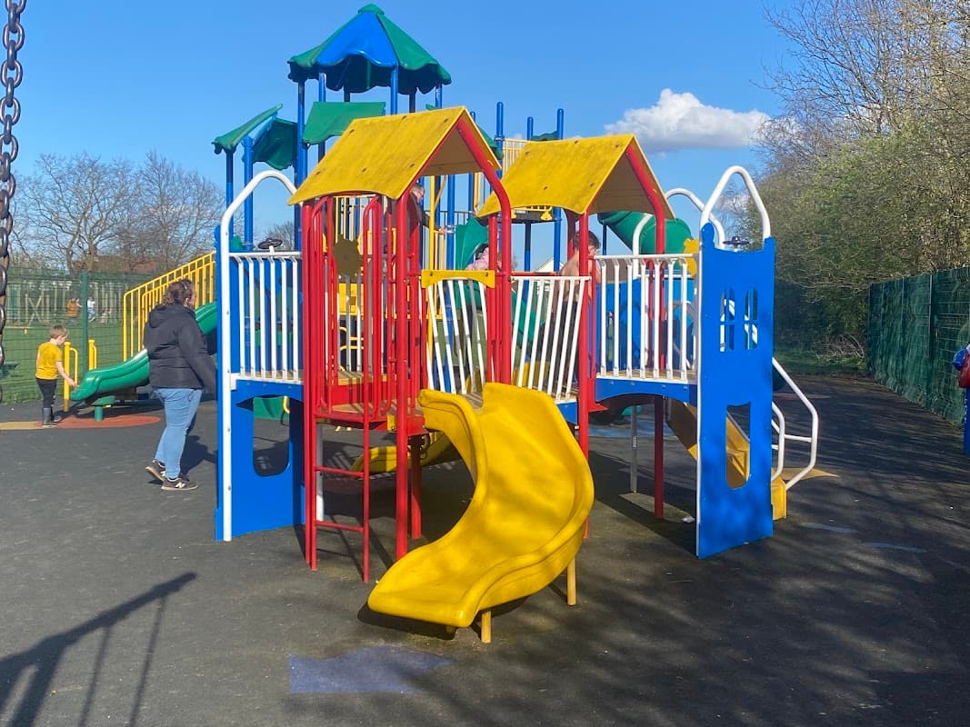 Colorful playground equipment with slides and climbing structures under a clear blue sky in a recreation area.