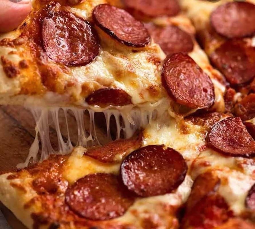 Cheesy pizza slice topped with pepperoni, with gooey cheese stretching from the crust.