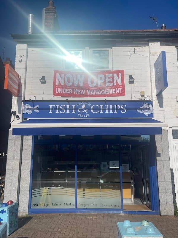 Brightly colored storefront of Thurcroft Fish Bar with a "NOW OPEN" banner and a blue awning displaying menu items.