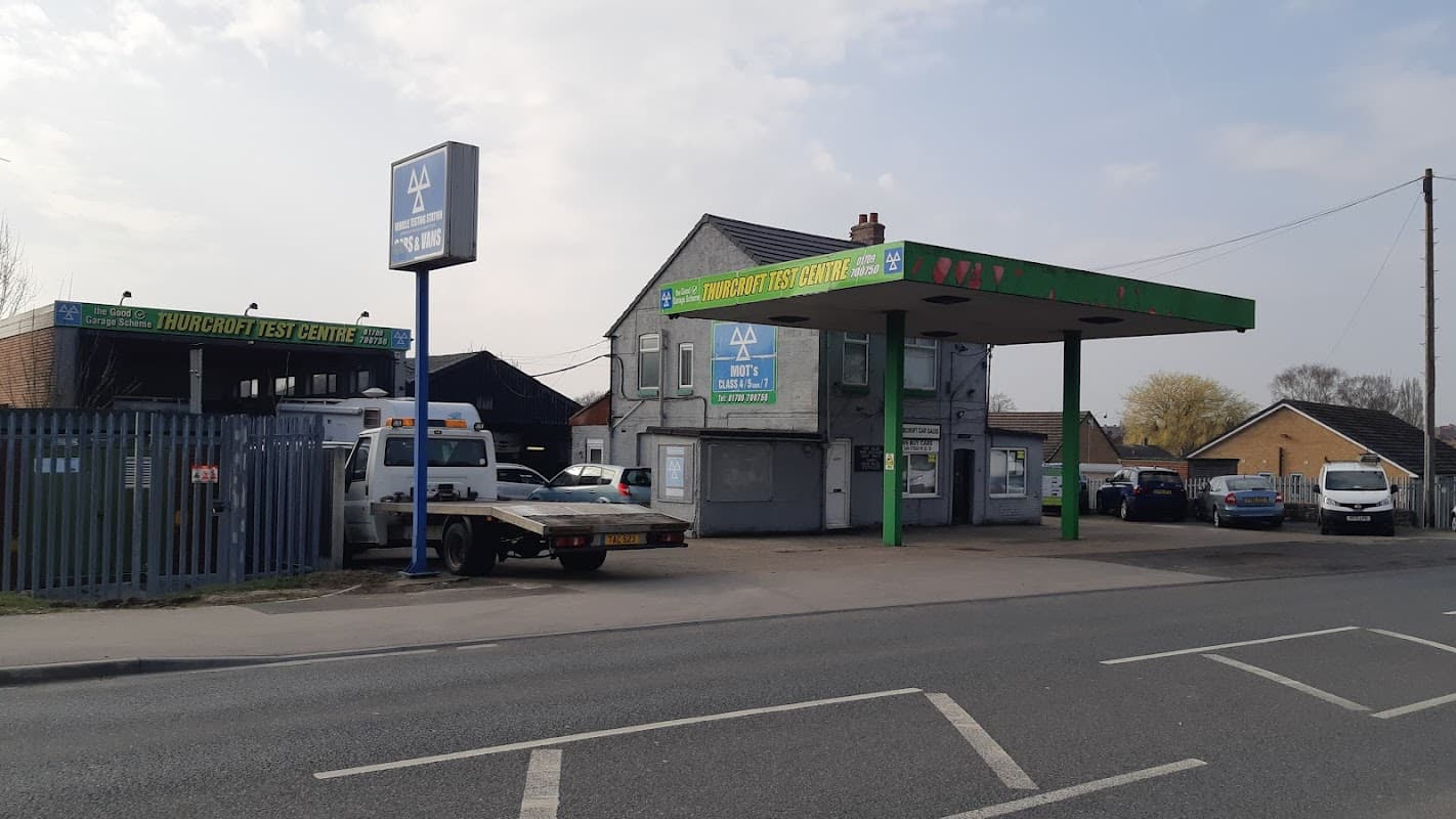Thurcroft Test and Auto Centre with a green canopy, sign, and parked vehicles along a roadside in Yorkshire.