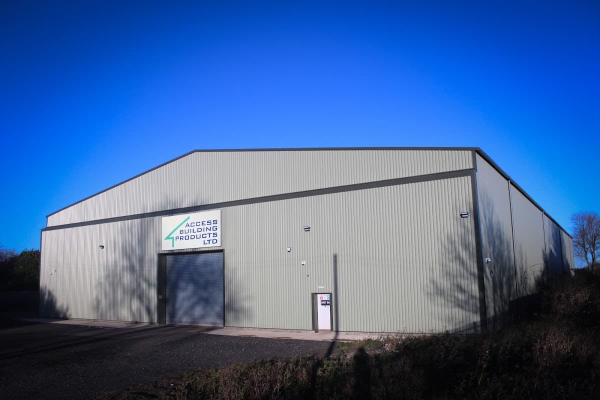 Large green industrial building with a sign for Access Building Products Ltd against a clear blue sky.