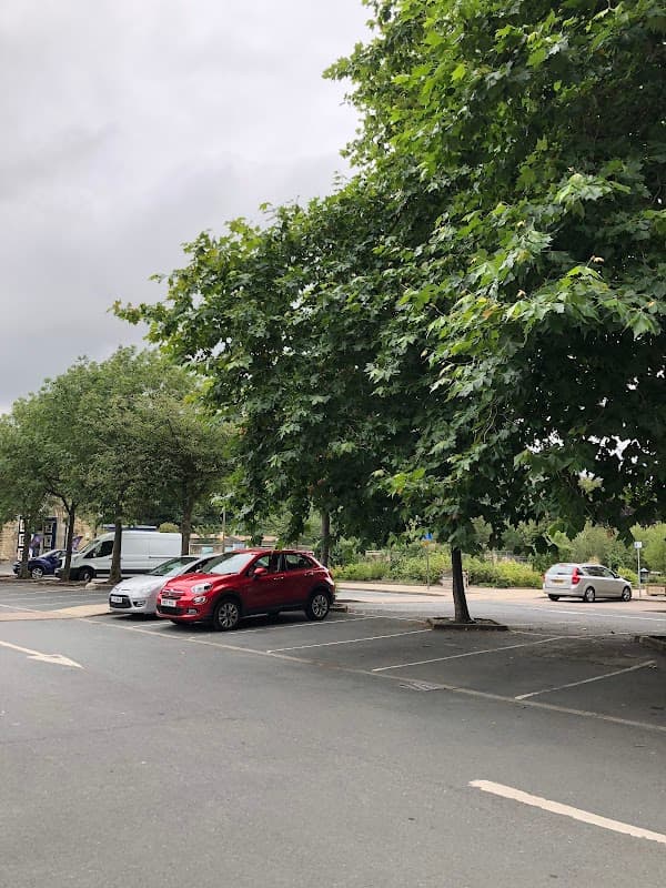 Bramsche Square car park with several trees and parked cars under a cloudy sky.