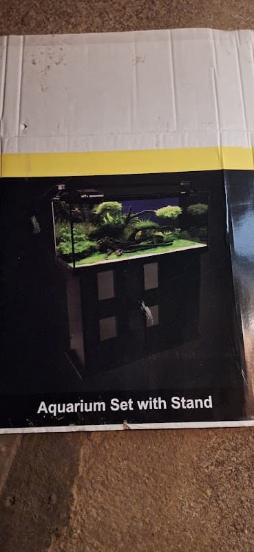 Aquarium set with stand displayed on a box, featuring lush aquatic plants and a dark background.