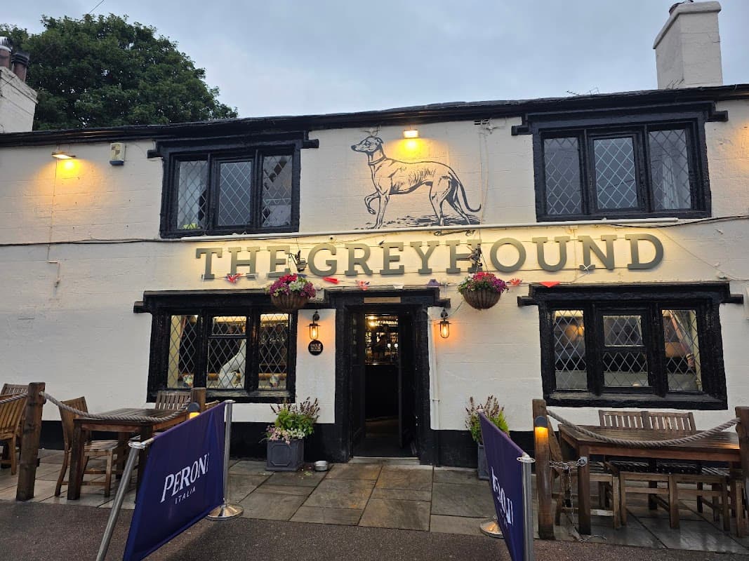 Historic restaurant with a greyhound logo, outdoor seating, and flower planters in Tong, Yorkshire.