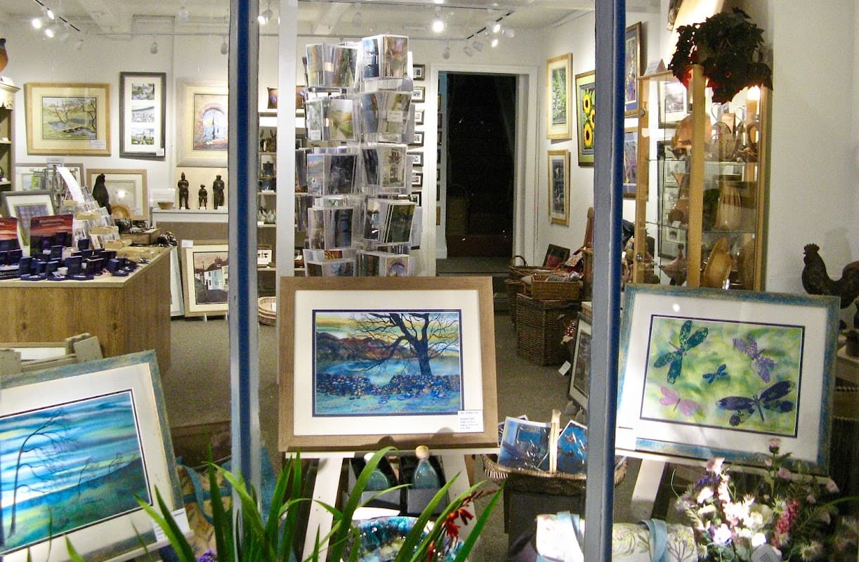 Art gallery display featuring framed artworks, sculptures, and various art supplies in a well-lit space.