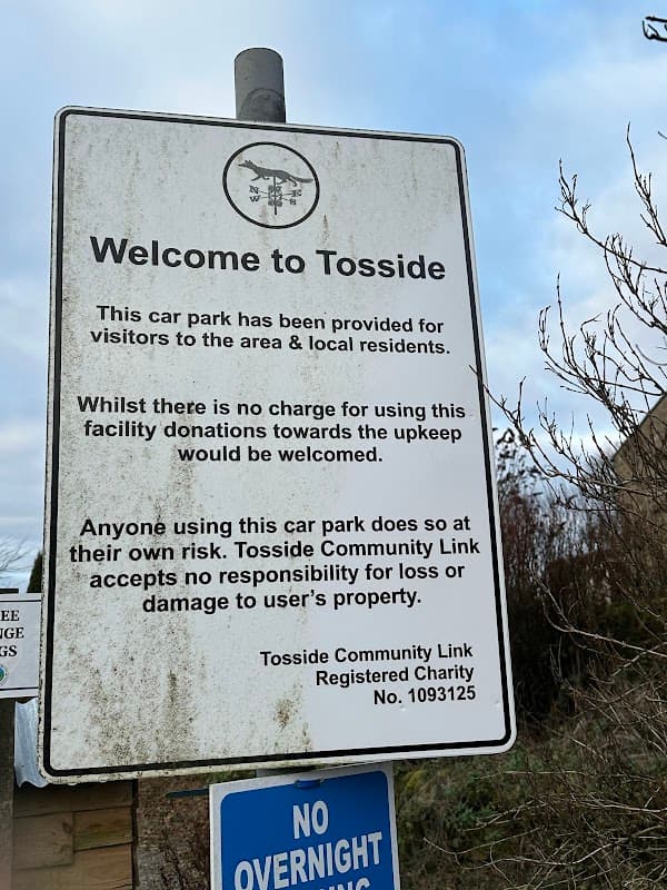 Welcome to Tosside sign detailing car park usage, charges, and liability information, with a blue no overnight parking sign below.