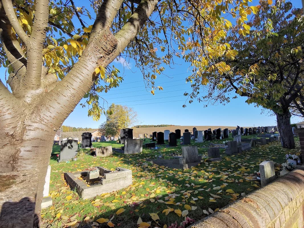 Wood Lane Burial Ground with gravestones, autumn leaves, and a clear blue sky in Treeton, Yorkshire.