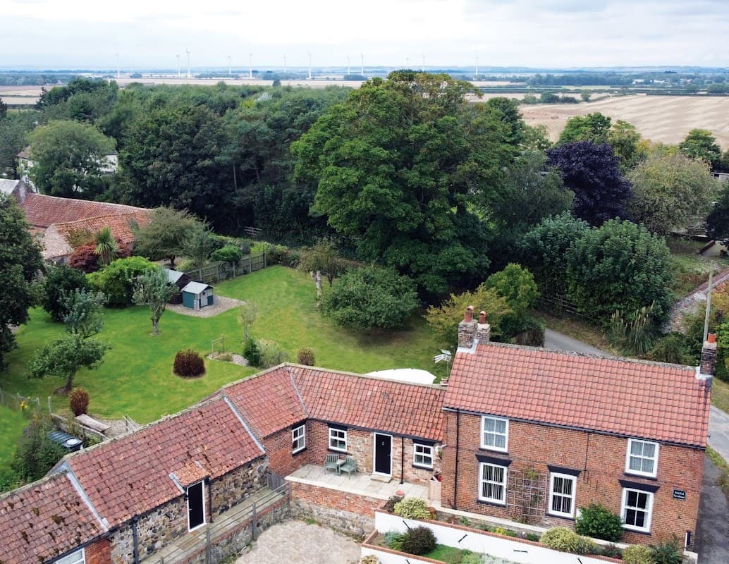 Aerial view of West End Farmhouse with gardens, trees, and fields in the background, set in a rural Yorkshire landscape.