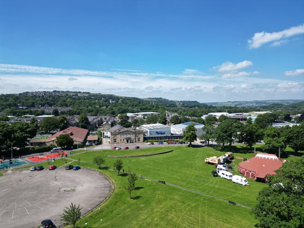 Aerial view of Victoria Park featuring green fields, a building, and a red circus tent under a clear blue sky.