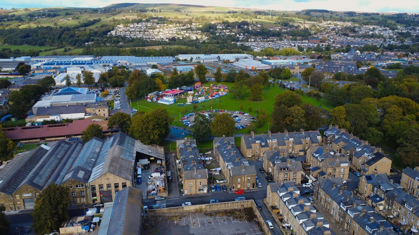 Aerial view of Victoria Park in Utley, Yorkshire, featuring green spaces, colorful structures, and nearby industrial buildings.