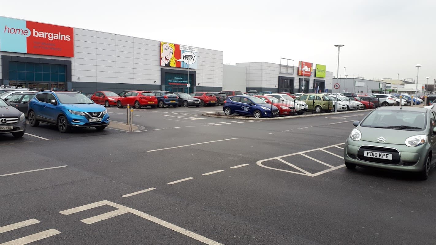 Car park at Beck Retail Park in Wakefield, featuring various parked cars and retail store signage.