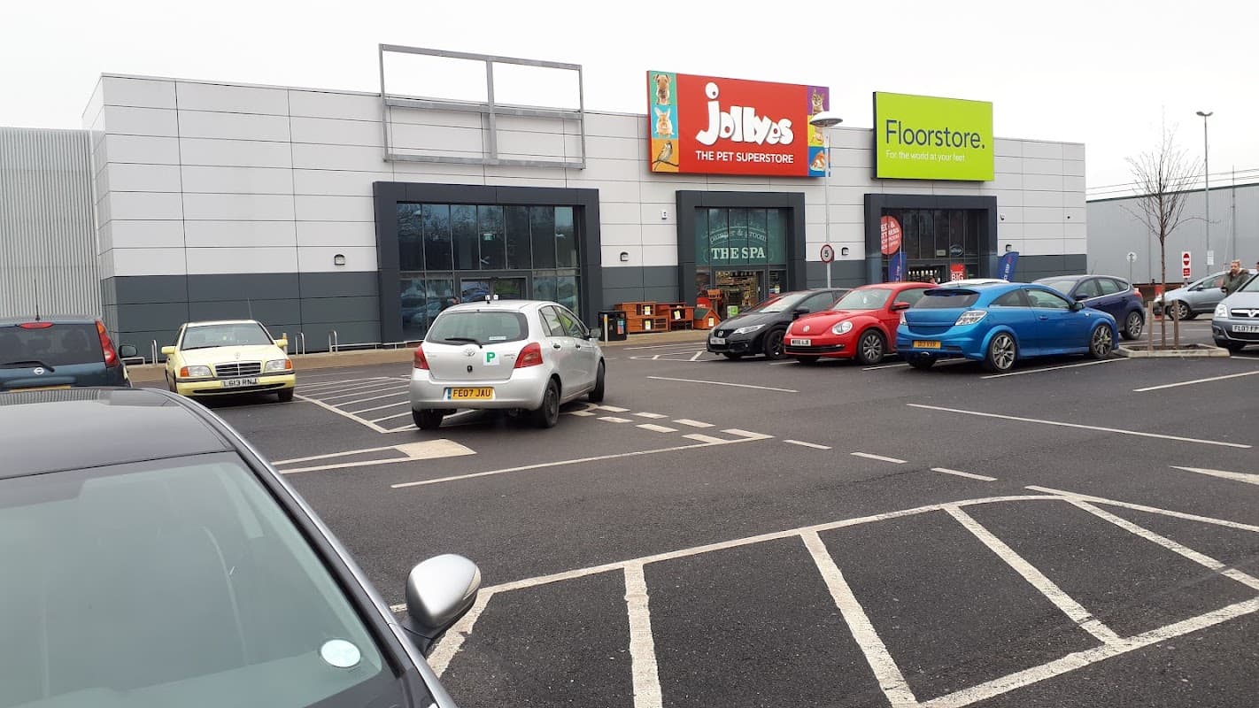 Jollyes pet supermarket and Floorstore signage at Beck Retail Park, with parked cars in the foreground.