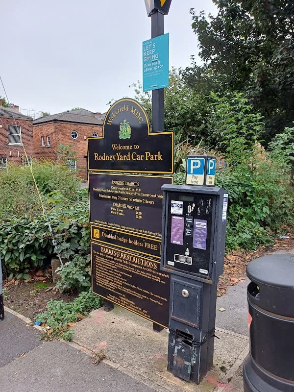 Sign for Rodney Yard Parking in Wakefield, featuring parking charges, restrictions, and a nearby payment machine.