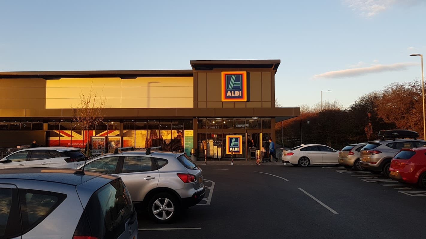 Aldi storefront at Snowhill Retail Park, with parked cars and evening sunlight illuminating the scene.