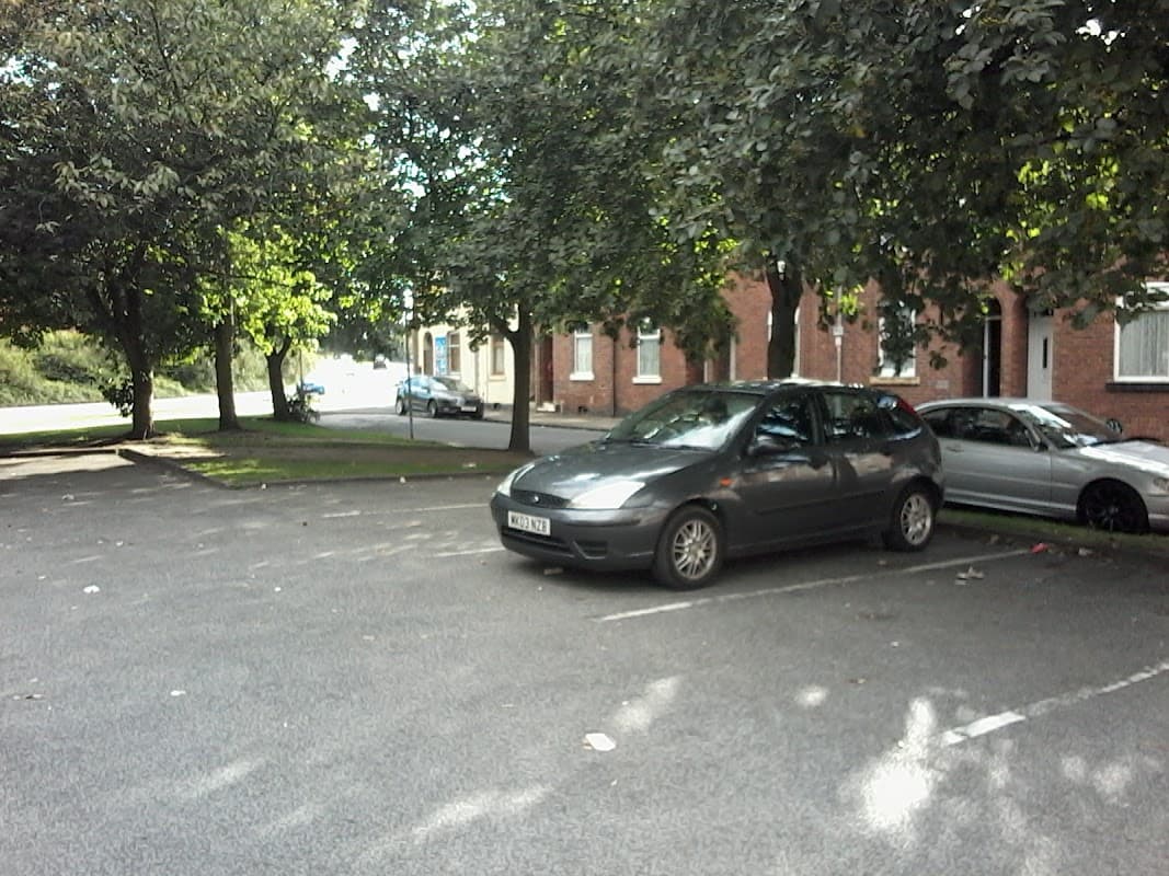 Free parking area with several cars and trees lining the edges in Wakefield, Yorkshire.