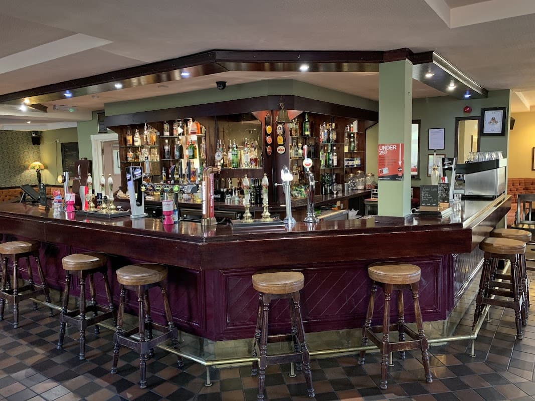 A wooden bar with stools, shelves of drinks, and a cozy interior in The Walkley Cottage, Walkley, Yorkshire.