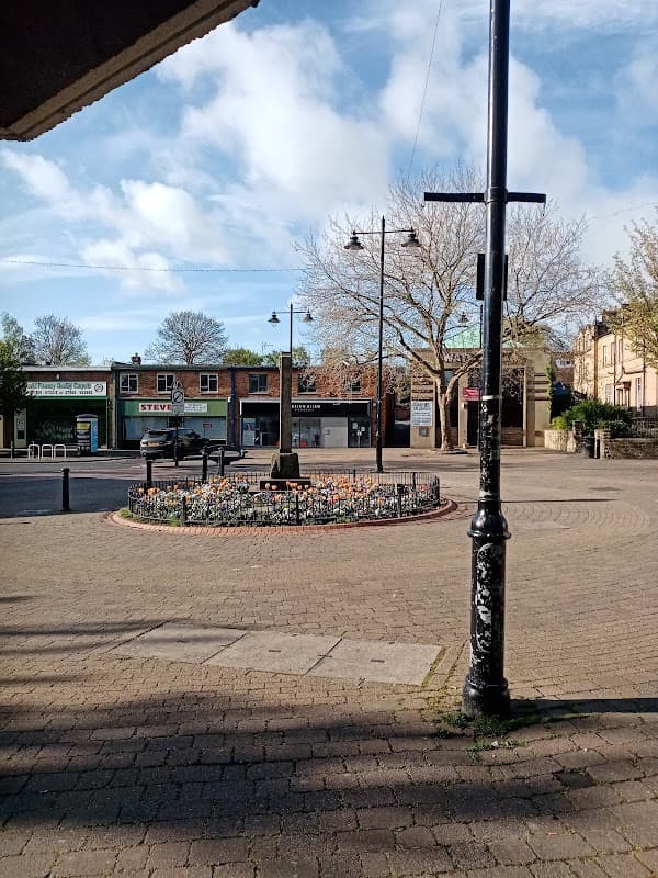 Biscay Way Car Park features a flower bed, lampposts, and storefronts under a partly cloudy sky in Wath upon Dearne.