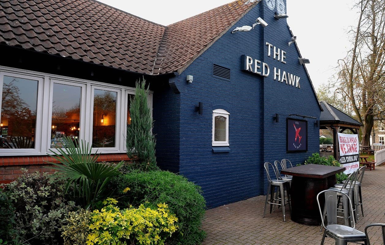 Exterior of The Red Hawk bar in Welton, Yorkshire, featuring a blue facade, outdoor seating, and greenery.