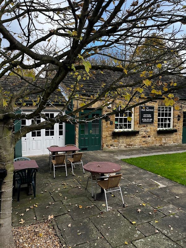Quaint stone restaurant with green doors, outdoor seating, and a tree shedding leaves in Wentworth, Yorkshire.