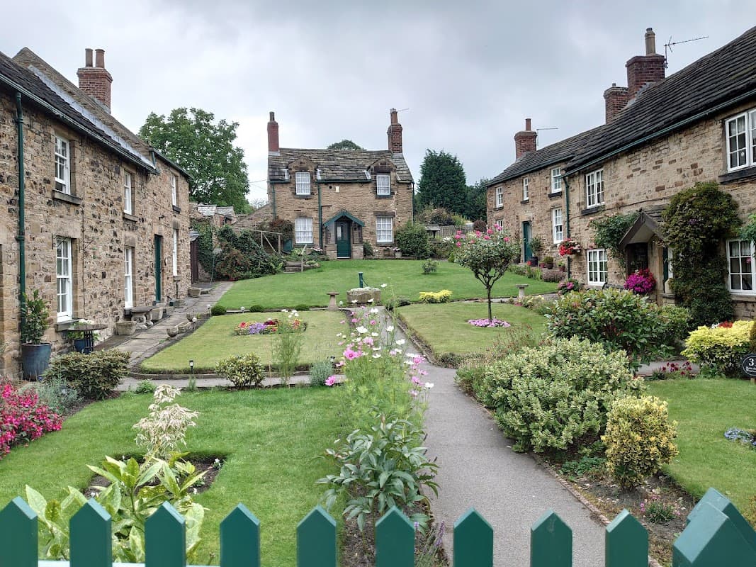 Quaint village scene with stone cottages, manicured gardens, and colorful flowers in Wentworth, Yorkshire.