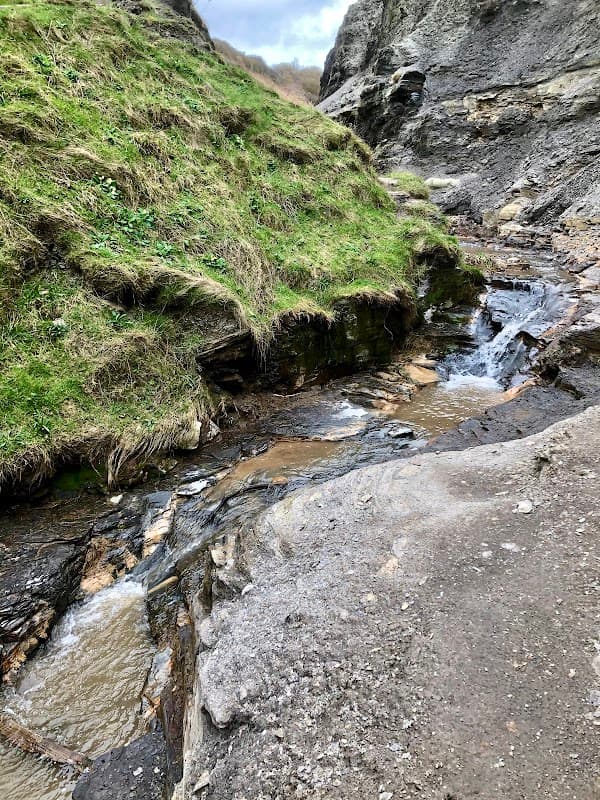 A small stream flows through rocky terrain with grassy banks in a scenic landscape of Westerdale, Yorkshire.