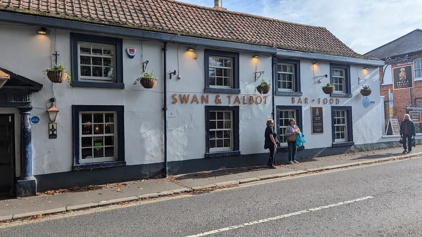 Swan & Talbot pub in Wetherby, featuring a white exterior, hanging plants, and people outside.