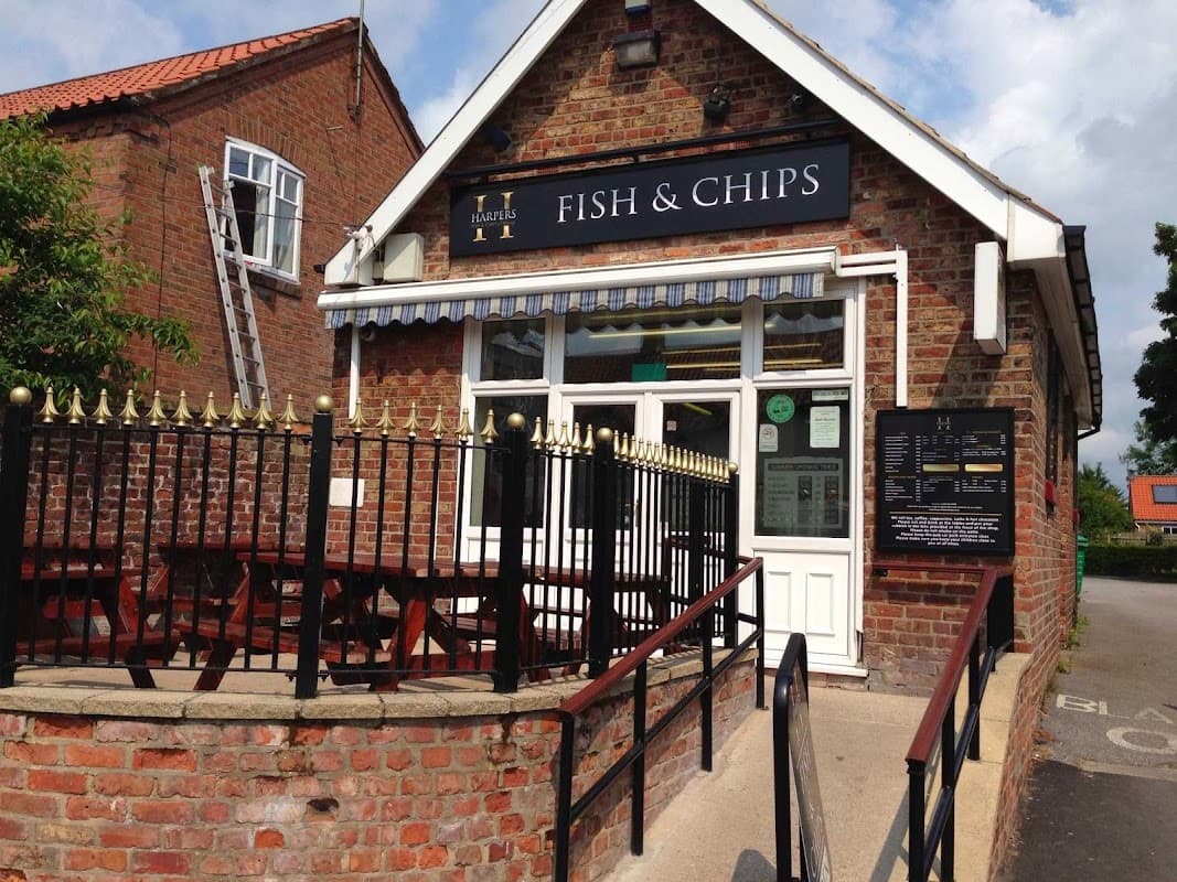 Brick restaurant exterior with a sign reading "Fish & Chips," outdoor seating, and a blue awning in Wetwang, Yorkshire.