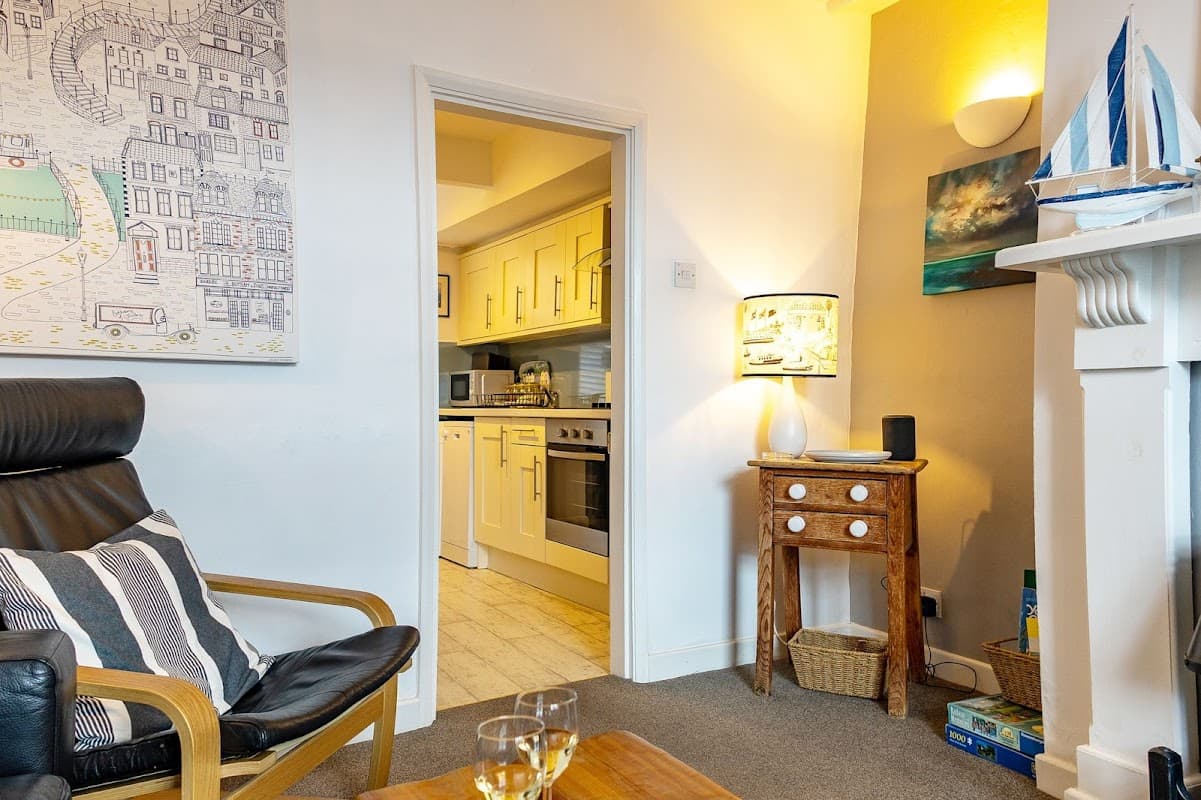 Coastguards Cottage interior featuring a cozy living area, kitchen entrance, and decorative nautical elements.