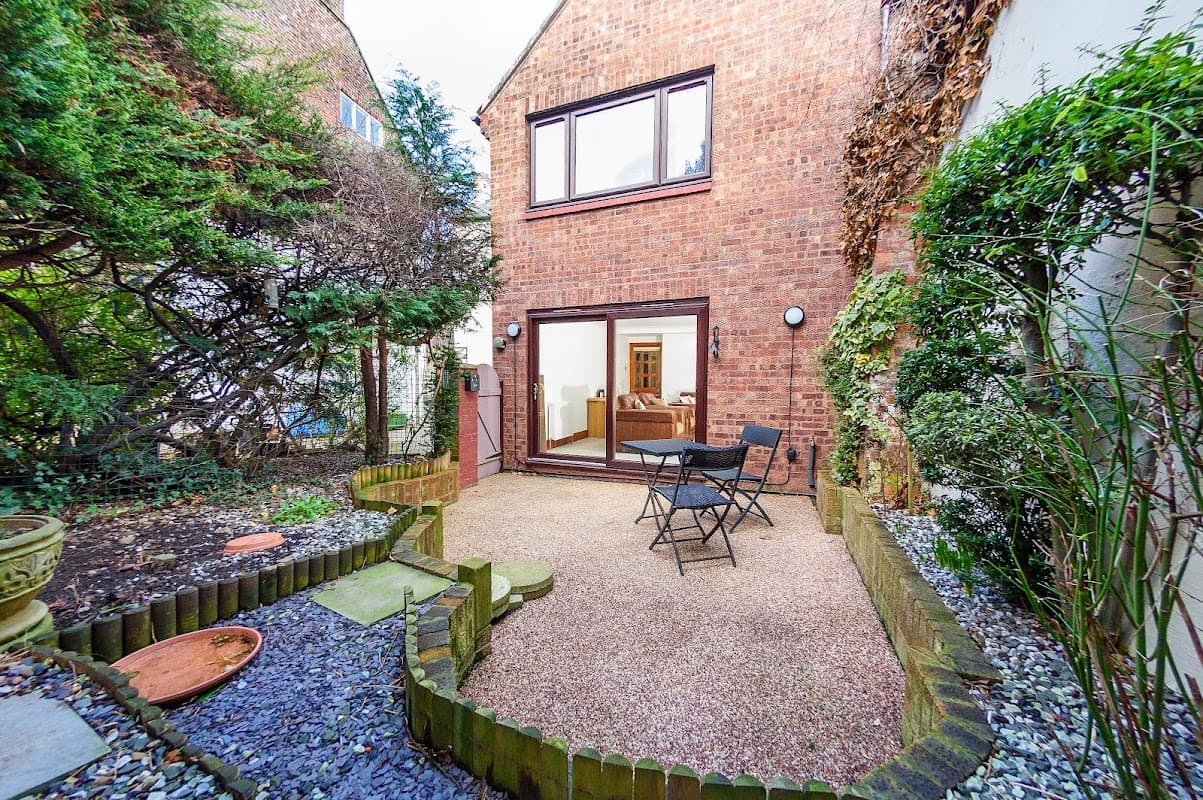 Cozy courtyard with gravel, potted plants, and a small table set for two, leading to a hotel interior in Whitby.
