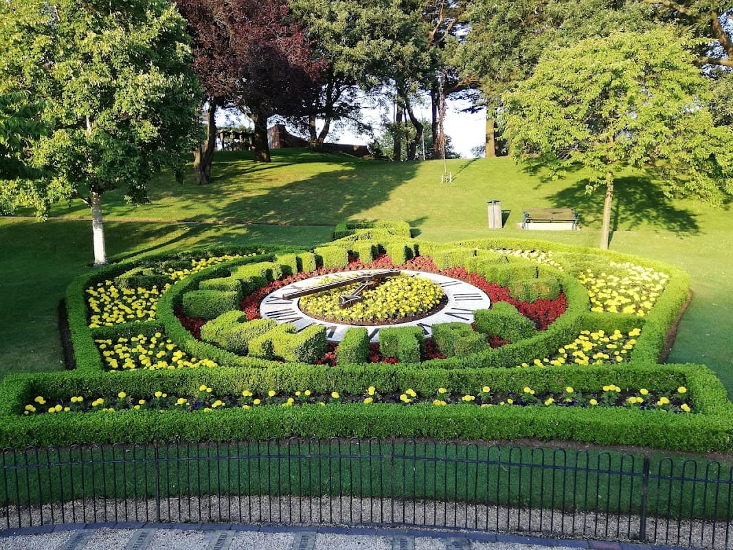 Colorful flower beds in a circular design, surrounded by lush green grass and trees in Pannett Park, Whitby.