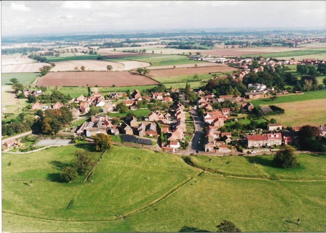 Aerial view of Whixley Village Hall surrounded by greenery, fields, and residential homes in Yorkshire.